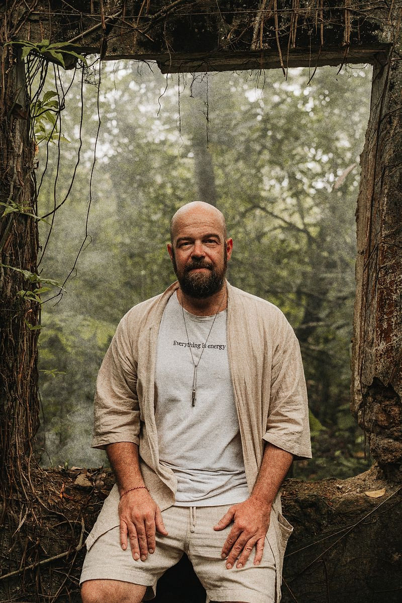 Gianluca Iacopini, sitting in a doorway of an overgrown ruin in the forest